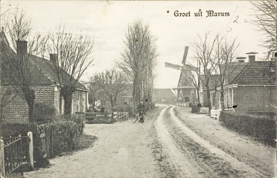 Achtkantige stelling korenmolen te Marum. Gezicht op de achterzijde door een straat met huizen. Kaart is verzonden op 19/9/1910.GRONINGEN-GRIJ-M_03263.0000009.1