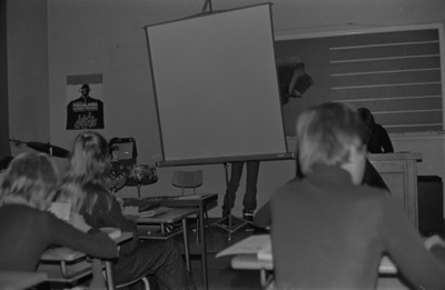 Oppilaita istumassa pulpeteissa luokassa