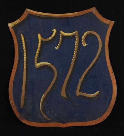 Wapenschild met tegen tegen blauwe achtergrond opschrift in goud-geel "1572"