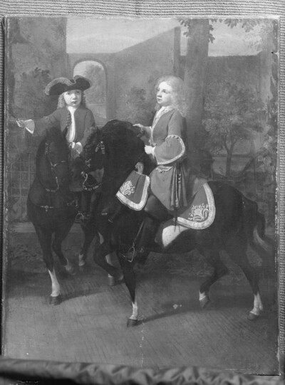 Two boys on horseback in front of a park