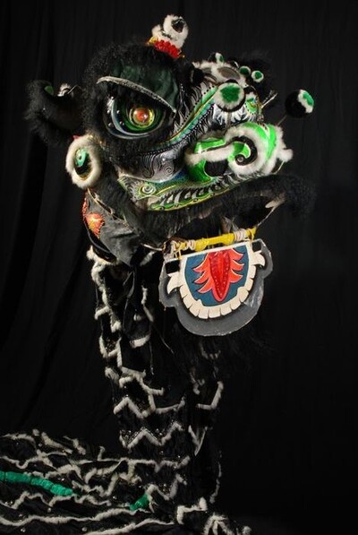 Fantastische kop van een Chinese leeuw, van metaal en papier maché, zwart en groen met elektrisch verlichte ogen, onderdeel van het danskostuum voor de leeuwendans