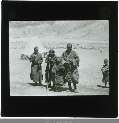 Native adults and two native children standing with mountain bases in the background