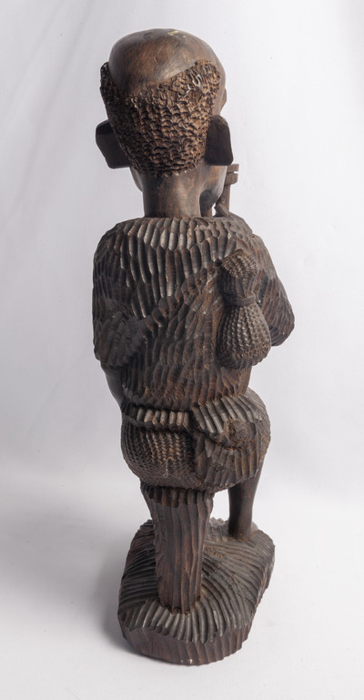 Statuetă din lemn sculptat reprezentând un bărbat cu pipă. Oferită cuplului Ceaușescu de Pamela Dos Santos, fondatoarea Organizației de Femei din Mozambic, cu ocazia vizitei oficiale în Mozambic, aprilie 1979.