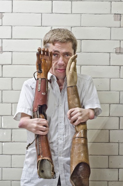 Mat Fraser holding two prosthetic arms at Blythe House | Europeana